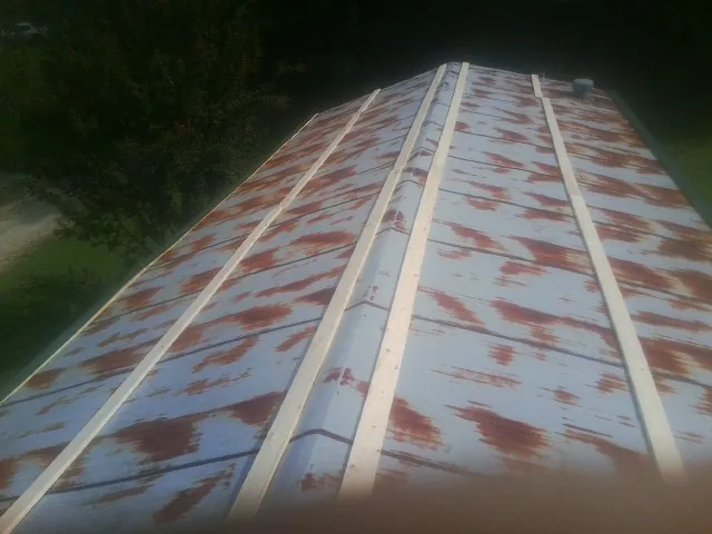 Rusted metal roof panels with new wood purlins before replacement — Storm Damage Roof Repair in Warrensburg by Roofing Brothers