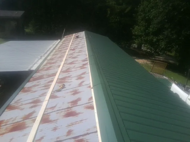 Old rusted panels beside newly installed green metal roofing — Wind Damage Roof Repair by Roofing Brothers in Warrensburg